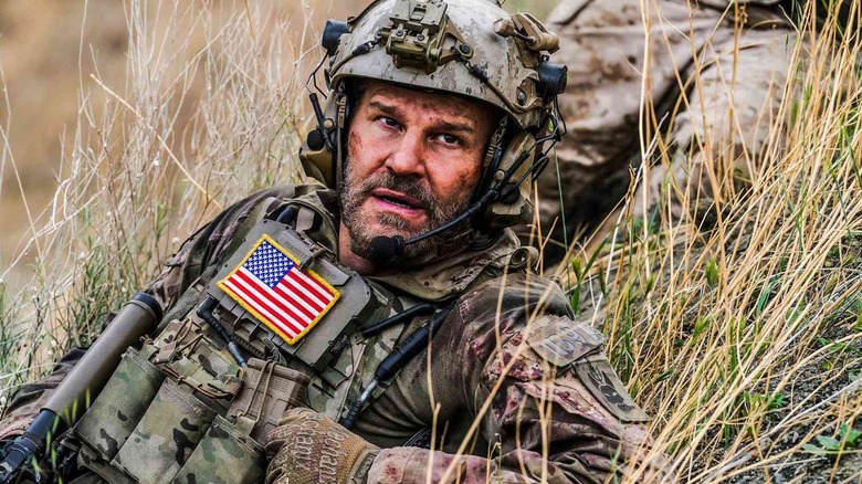 Jason Hayes (David Boreanaz) reclines in tall grass in SEAL Team