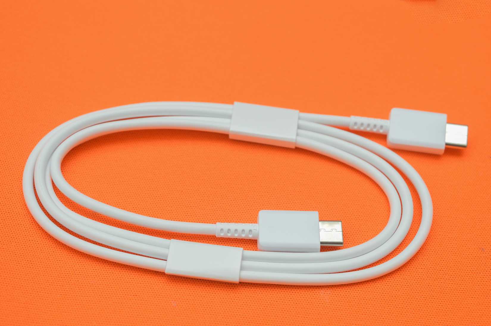 A white USB-C cable on an orange background