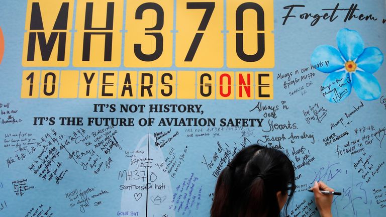 A woman writes a message on a board during 2024's annual remembrance event for missing flight MH370. Pic: AP
