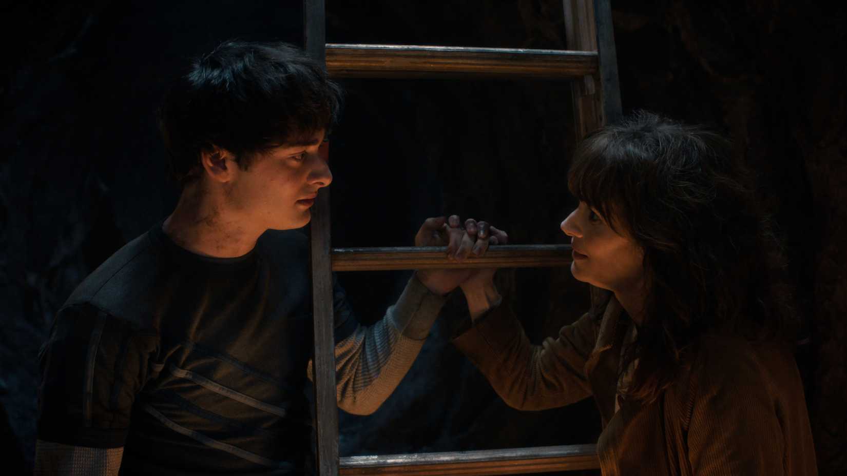 Will Byers (Noah Schnapp) talks to his mom, Joyce Byers (Winona Rider) while holding the rungs of a ladder in Stranger Things season 5