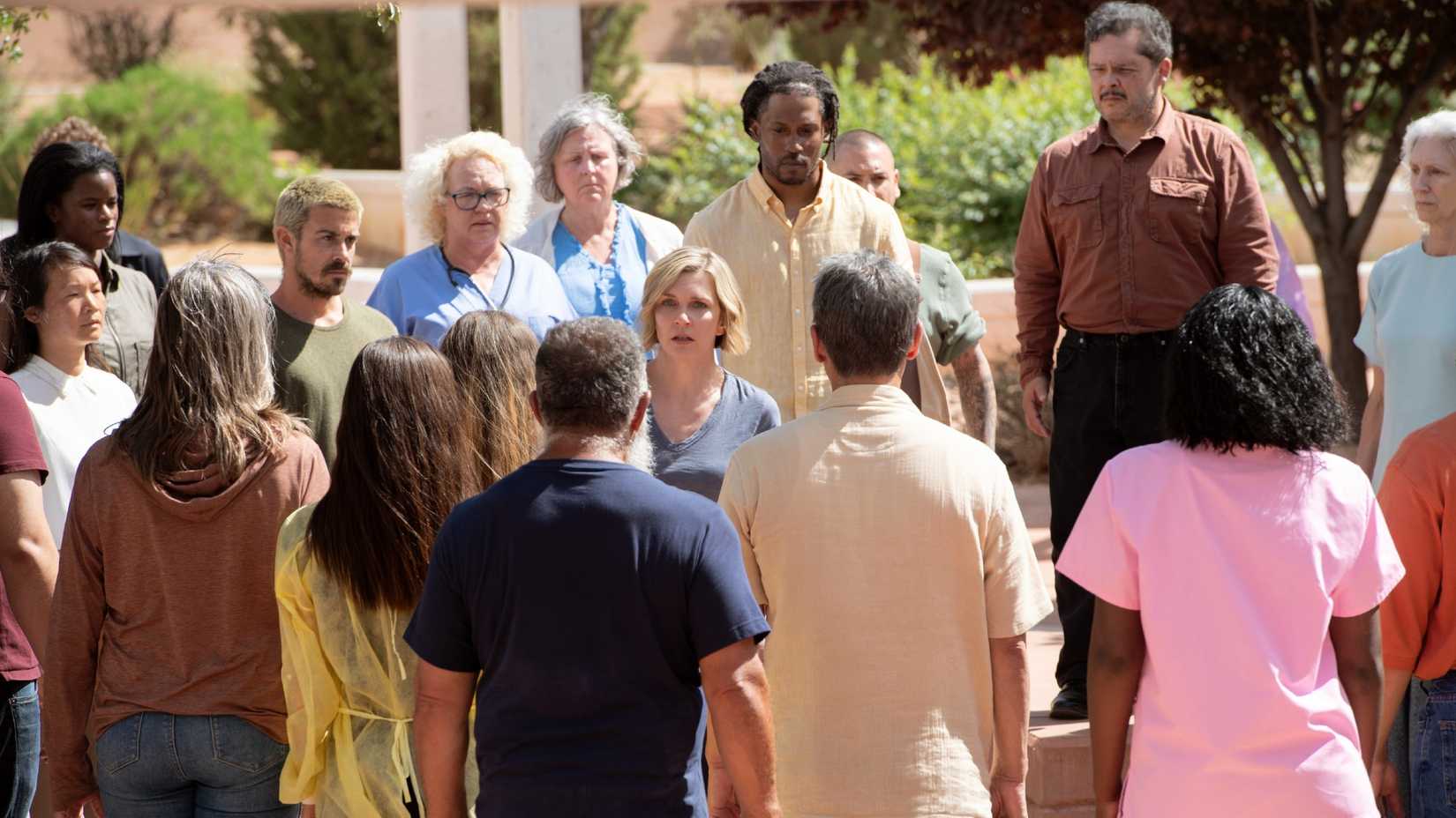 A crowd of the hive mind gathered around a Carol Sturka (Rhea Seehorn) in Pluribus