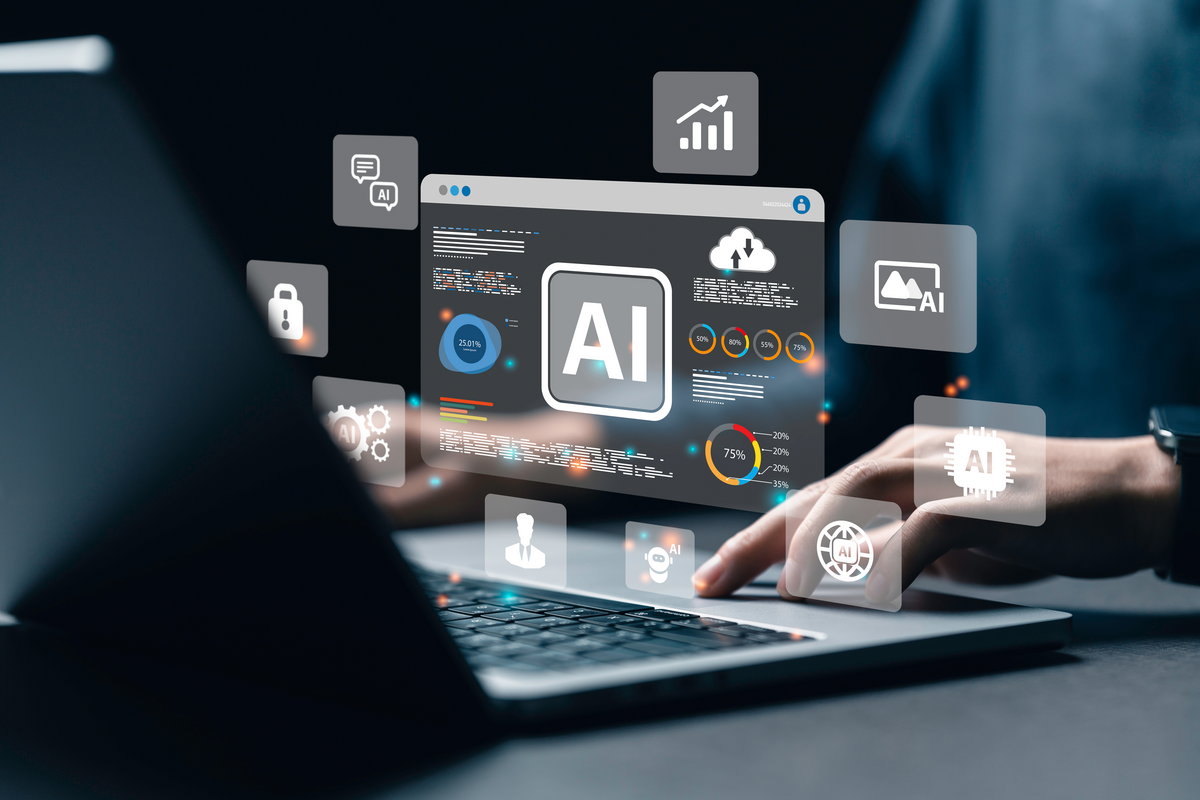 Digital icon labeled AI is projected above a laptop as a person uses the device.