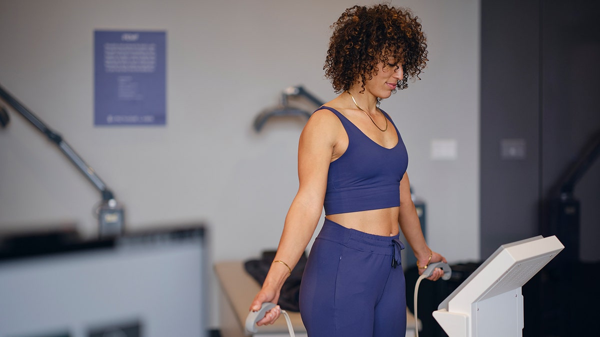 woman stands on body composition analysis machine holding probes