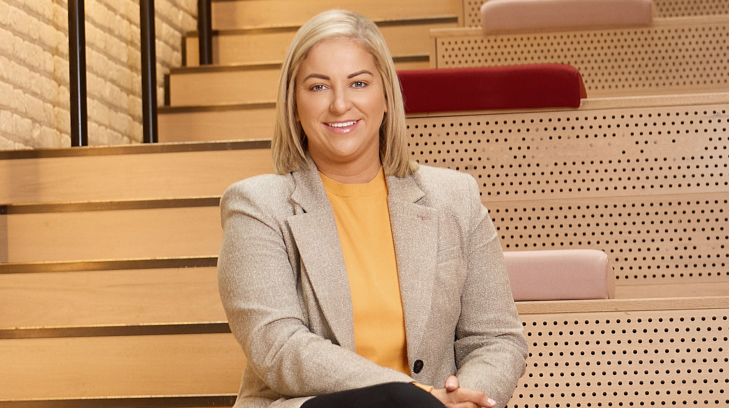Man standing by a brick wall and woman sitting on steps.