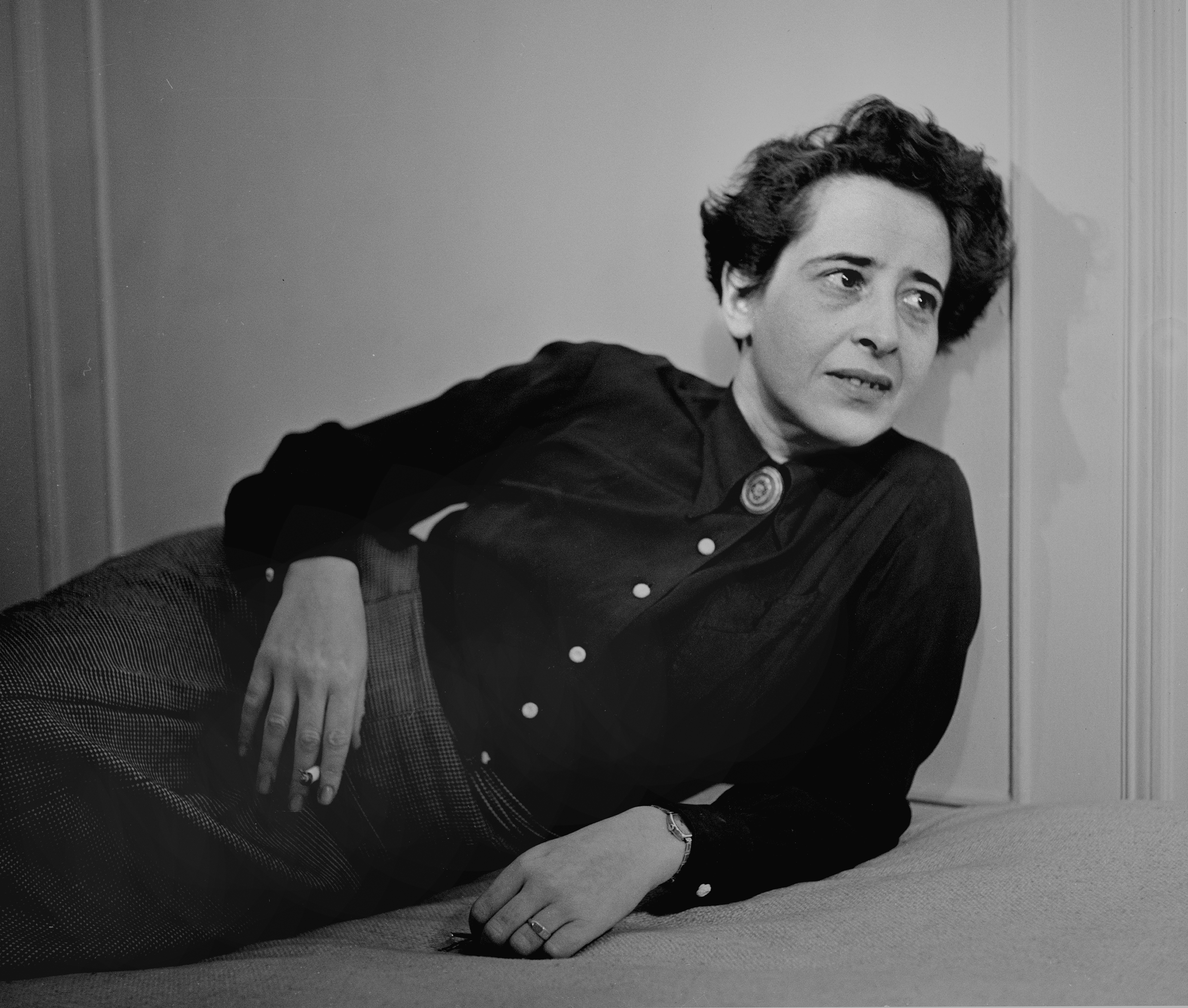 Portrait of political theorist Hannah Arendt lying down, looking away, with a cigarette in her hand.