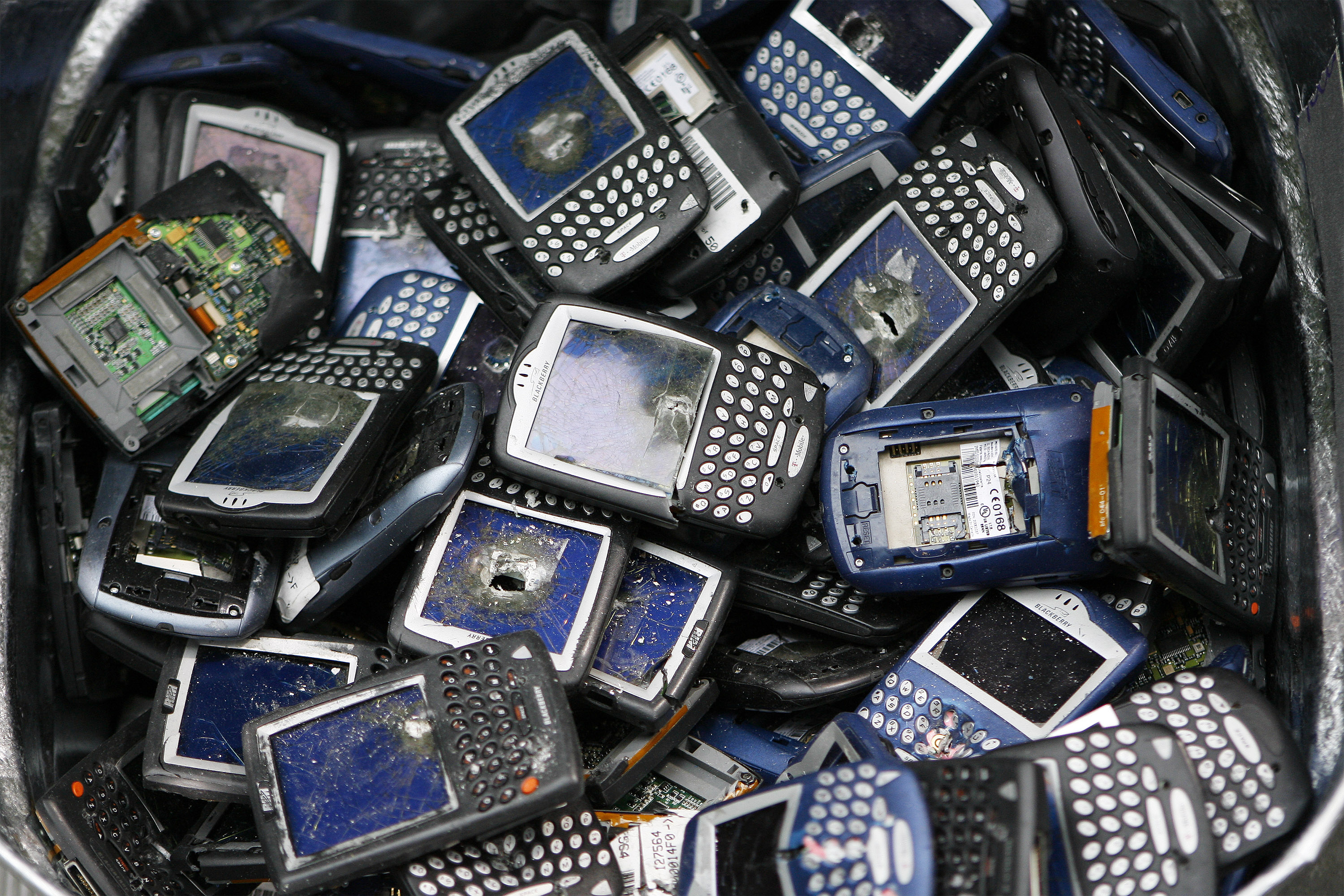 Trashed Blackberry phones sit in a bucket.