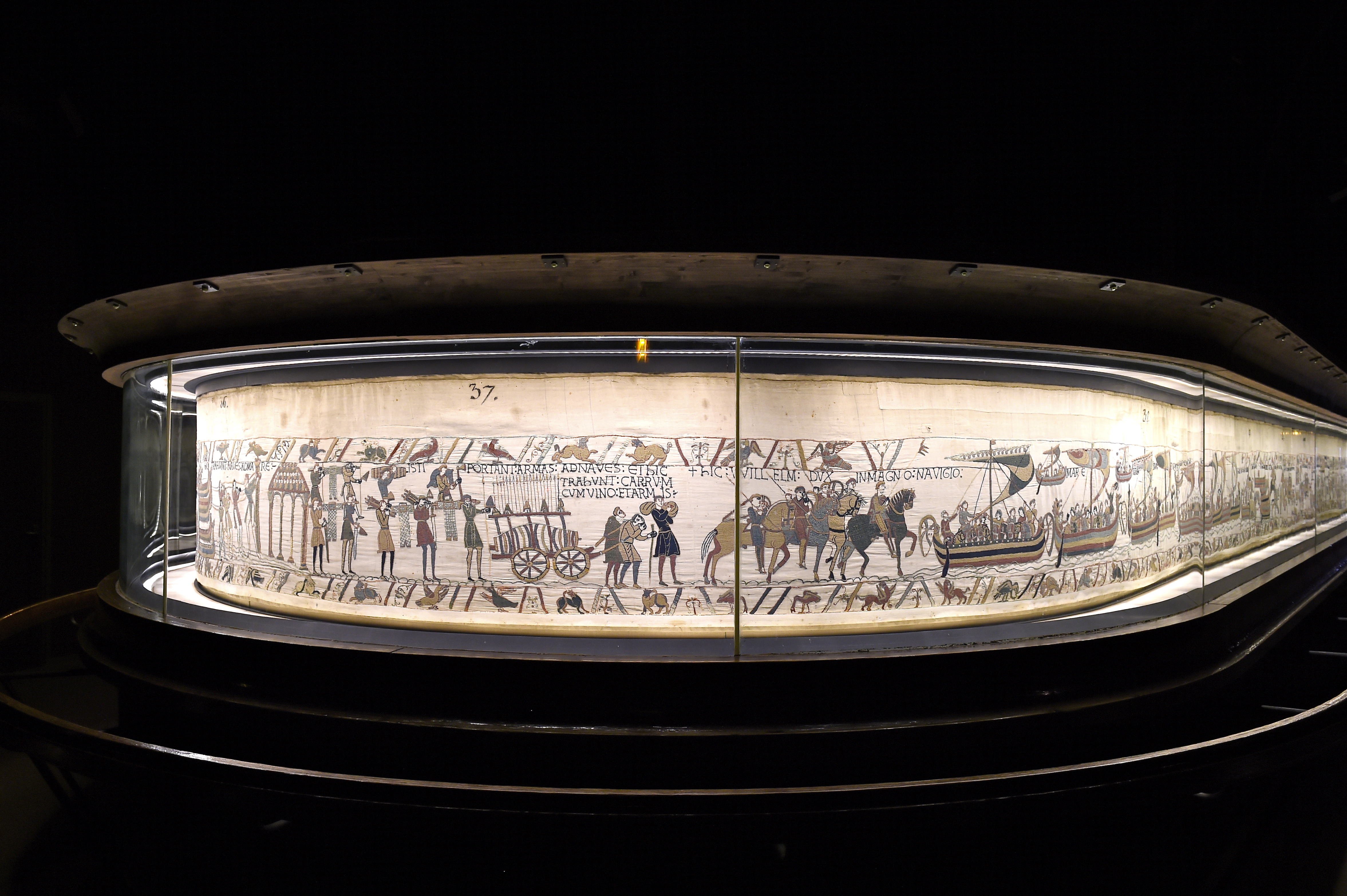 The Bayeux Tapestry depicting the 1066 Norman invasion and Battle of Hastings, encased in glass.