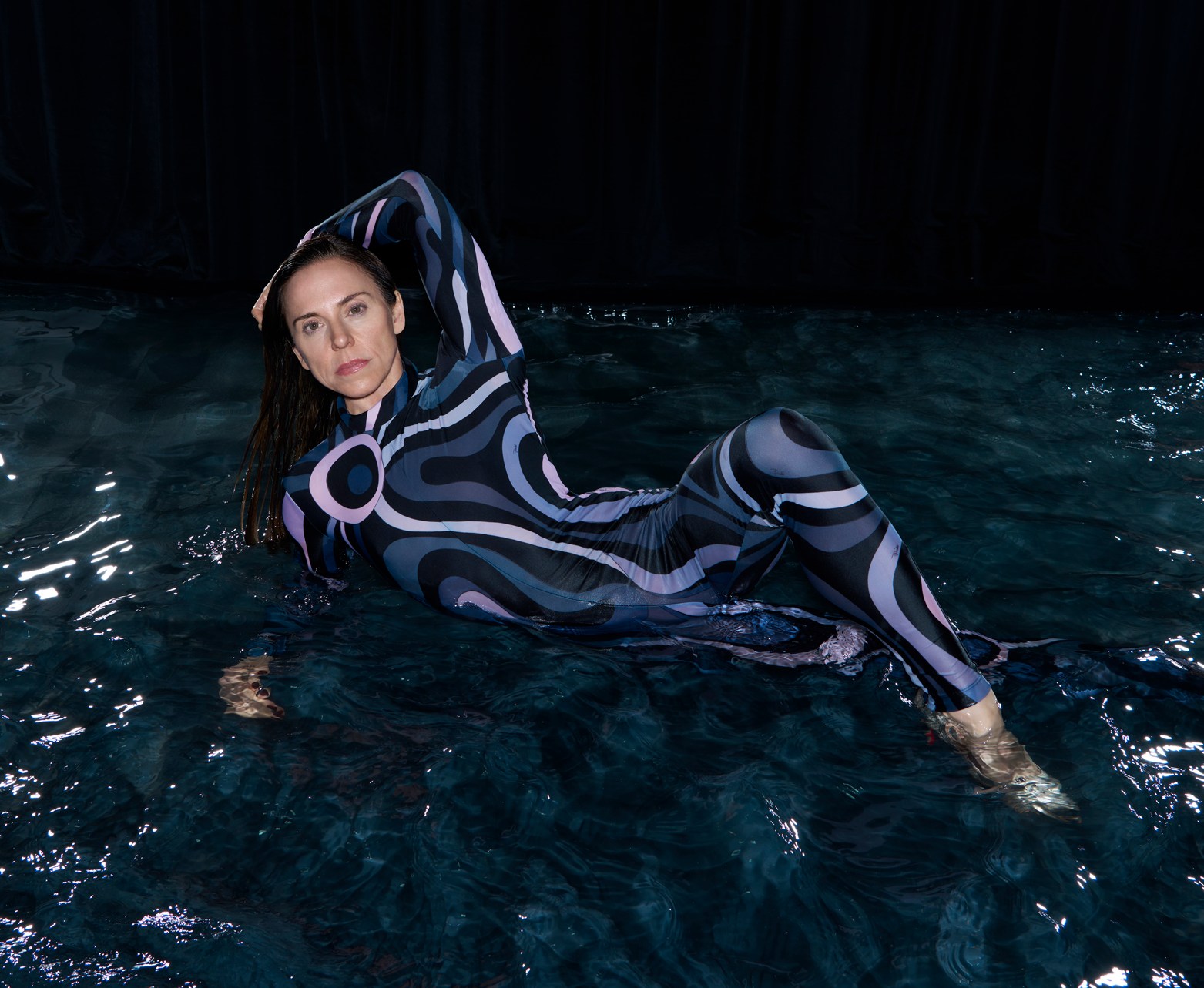 Melanie Chisholm of Spice Girls in a patterned swimsuit, submerged in water.