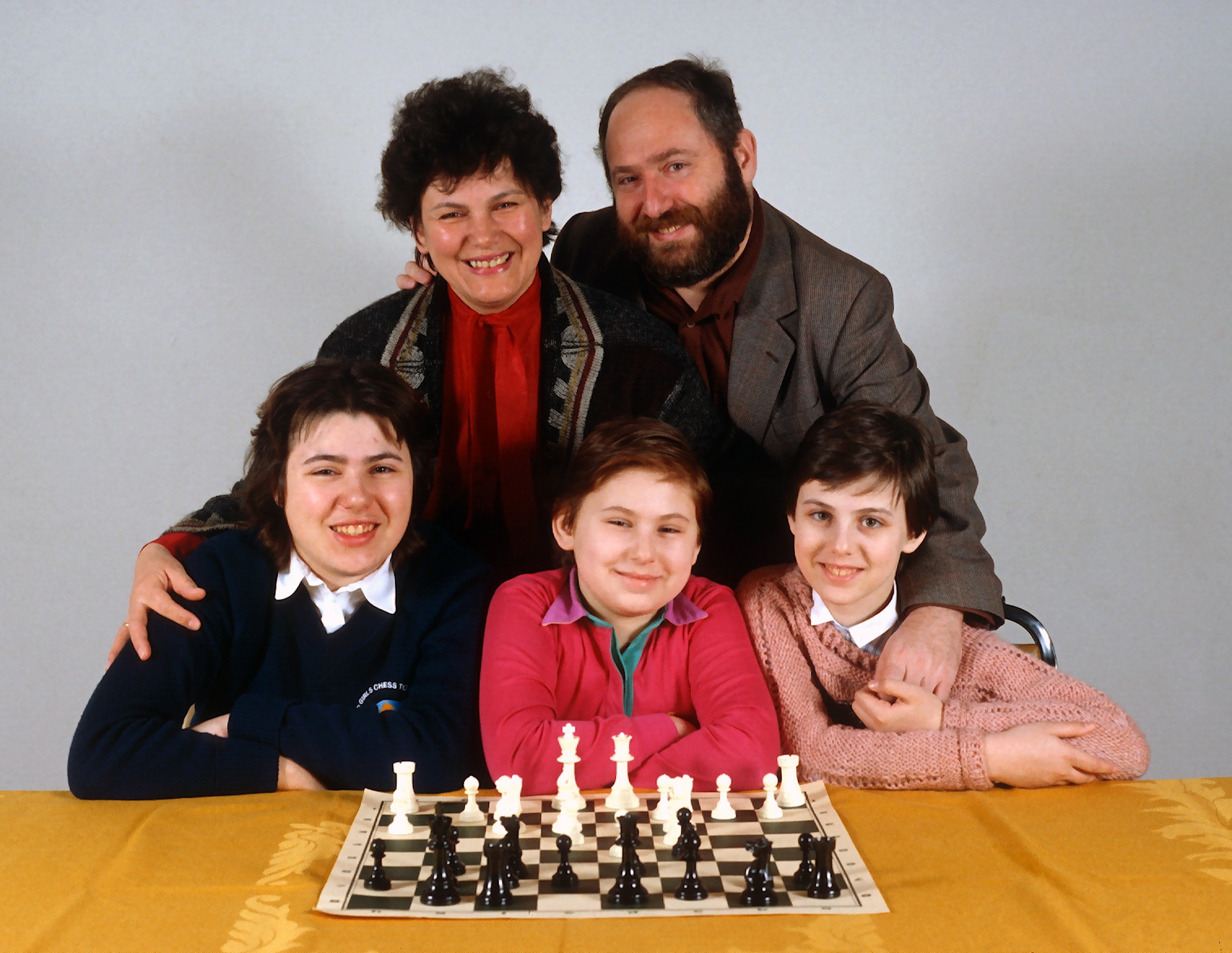 The Polgar family, with parents Laszlo and Klara behind their daughters Sofia, Judith, and Susan, sitting at a chessboard.