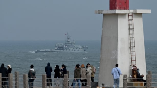 A China People's Liberation Army tugboat sails in the Taiwan Strait, past tourists on Pingtan island, which the closest point to Taiwan in 2023