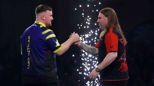 Luke Littler of England shakes hands with Ryan Searle of England after victory in their semi-final match at Alexandra Palace on January 02, 2026 in London, England.