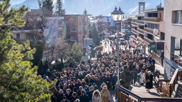 A large procession makes its way through the streets of a town