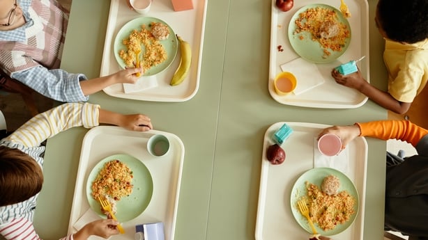 A birds eye image of four school children sitting at a table eating meals on dinner trays