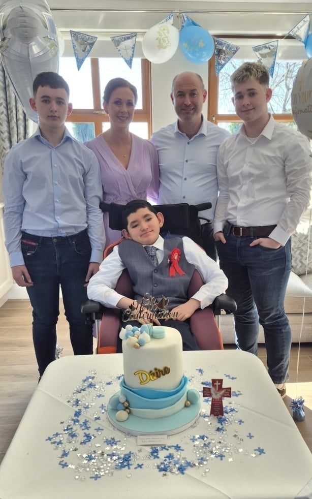a family photograph at a celebration with cake and balloons