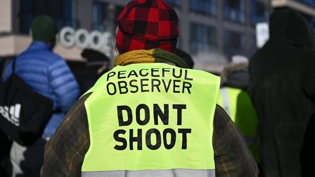 A person with an observer vest reading 'Don't Shoot' joins onlookers after federal agents allegedly shot a protestor in Minneapolis