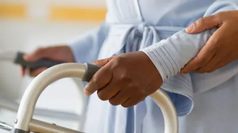 Getty Images A person is walking with a zimmer frame