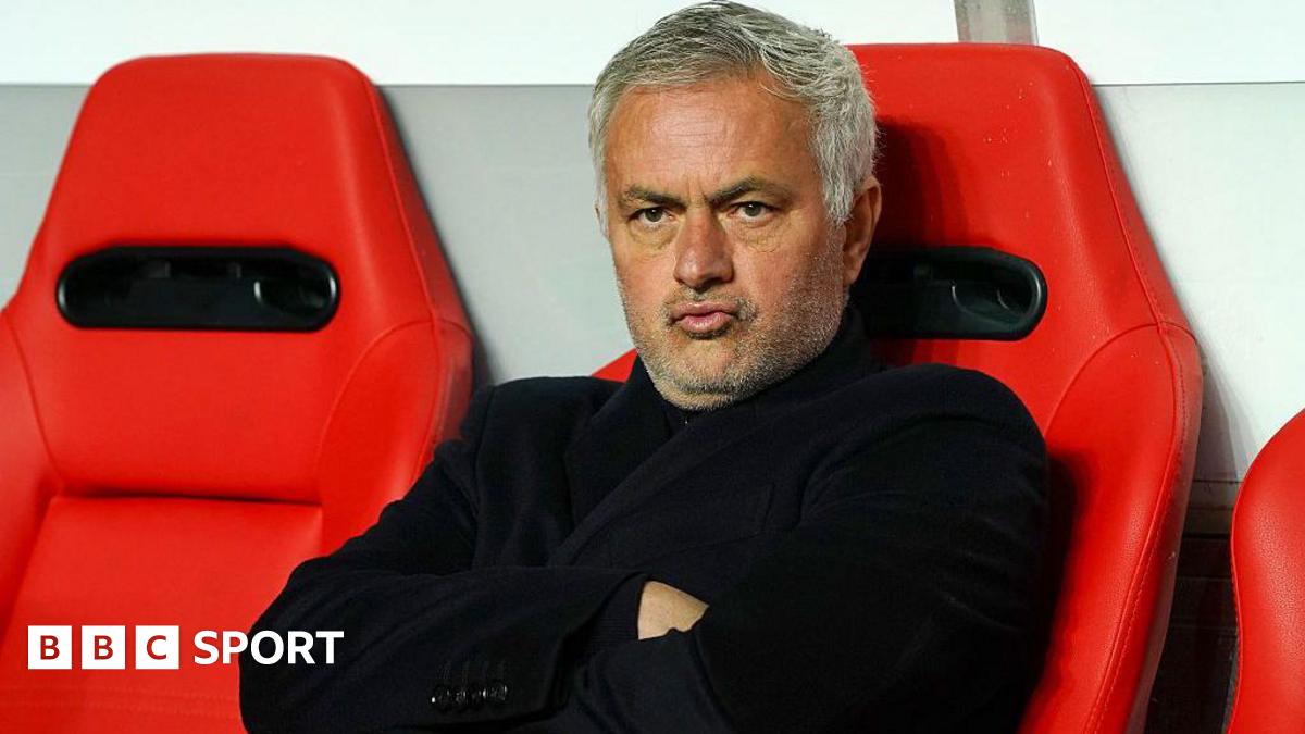 Jose Mourinho purses his lips and cross his arms as he sits on a red chair