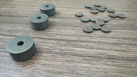 BBC There are three objects on the left and more than a dozen smaller objects shaped like coins on the right.