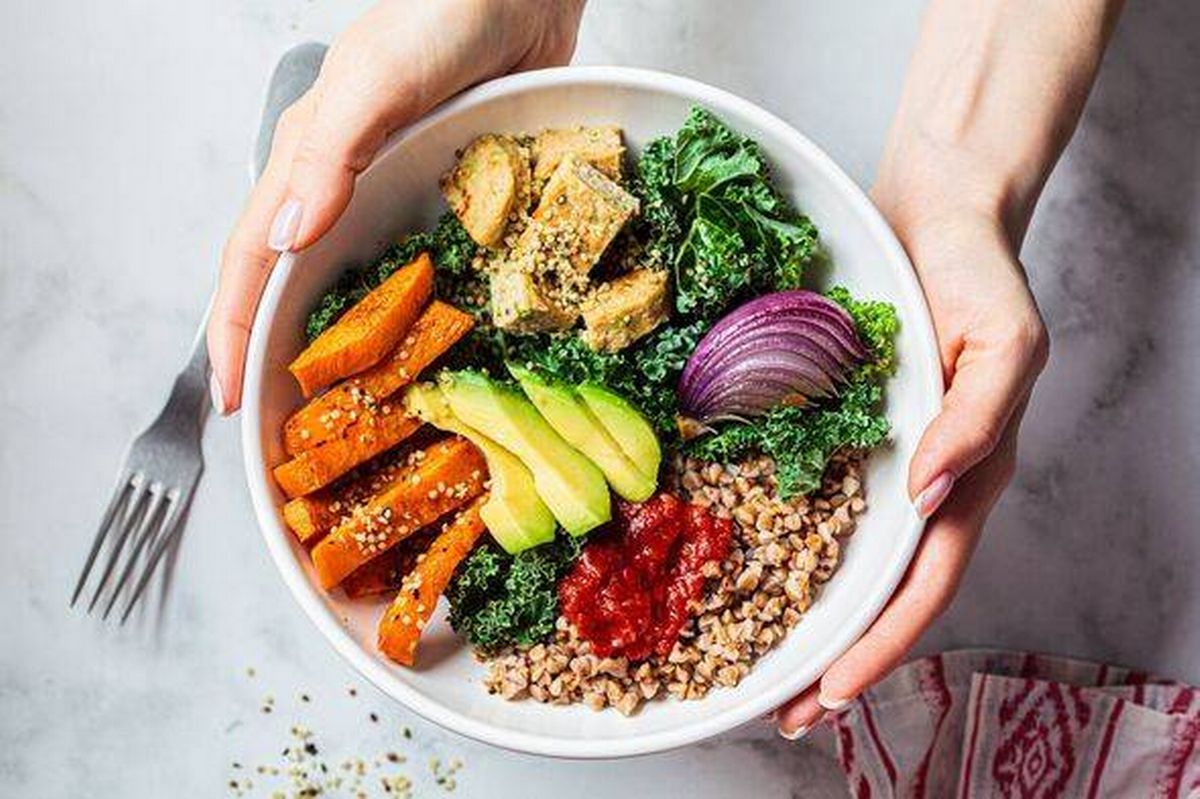 Baked vegetables, avocado, tofu and buckwheat buddha bowl. Vegan lunch salad with kale, baked sweet potato, tofu, buckwheat and