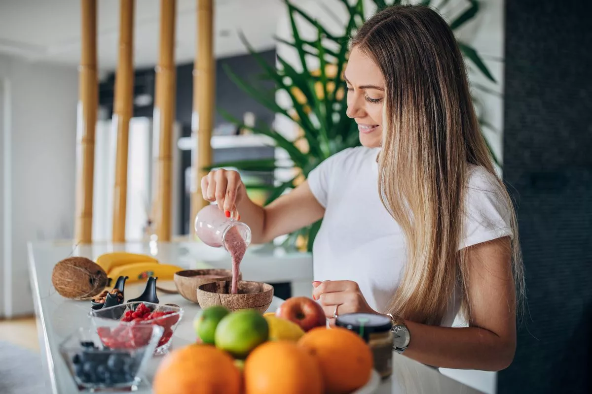 Woman preparing healthy summer breakfast. Smoothie bowl with fresh fruits