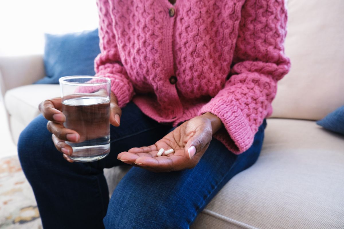 Close-up of unrecognizable black woman sitting on couch holding medication