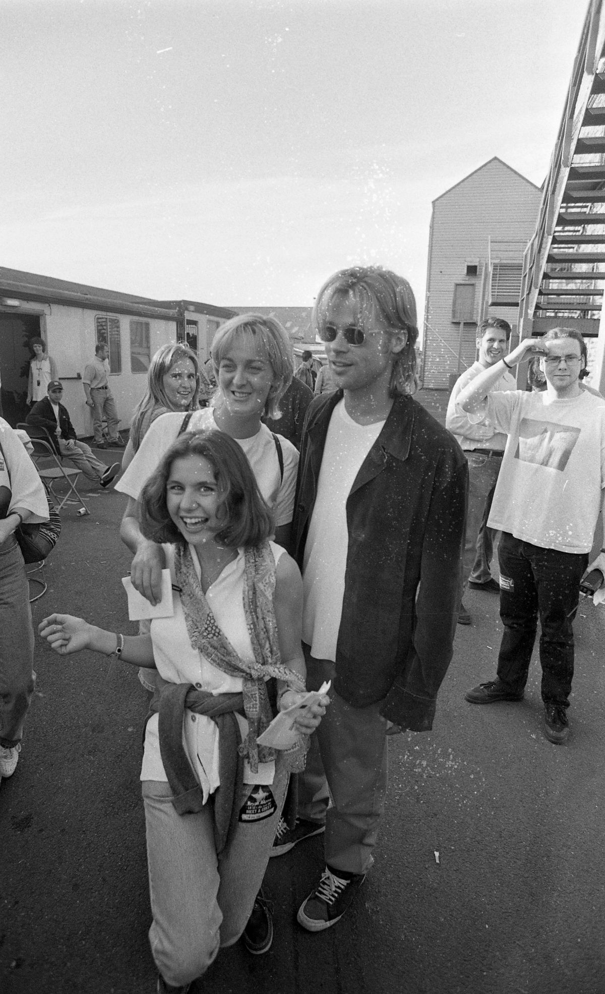 A black and white photo of Brad Pitt signing autographs and taking pictures with fans after the Bryan Adams concert at The Point Depot in Dublin, 22/07/1996