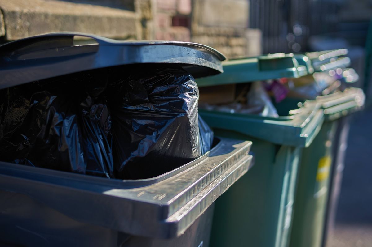 Gray and green garbage cans overfilled with domestic refuse