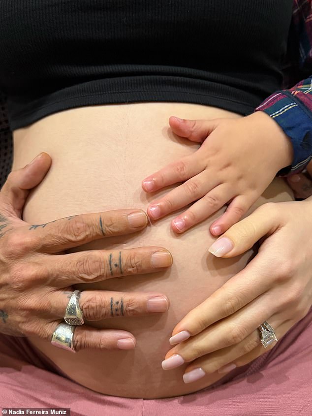 He placed his tattooed hand on her baby bump in this new image shared by his wife; also in the image is the hand of their first child, son Marco, aged two