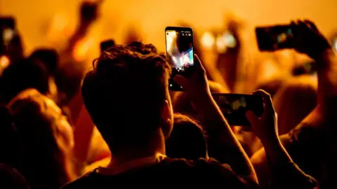 Getty Images A crowd film a concert on their phones
