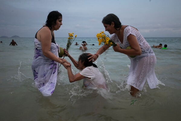 People pray on Copacabana Beach during a ceremony honoring Yemanja, the sea goddess of the Yoruba religion, a New Year's tradition in Rio de Janeiro, Brazil, Dec. 29, 2025. (AP Photo/Bruna Prado, File)