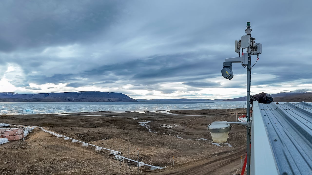 a radar camera positioned on a poll, overlooking land and ocean