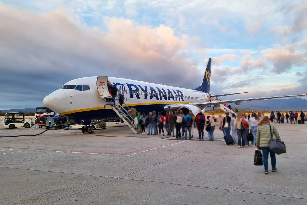 Girona, Spain, October 5, 2024: A bustling airport scene with passengers lined up to board a ryanair aircraft as the sun sets in the background. the image anticipation and movement typical of travel hubs.