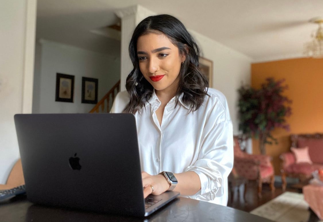 Woman sitting at a table on a laptop.