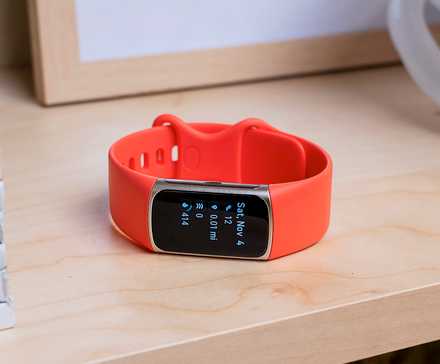 A Fitbit fitness tracker on a shelf.