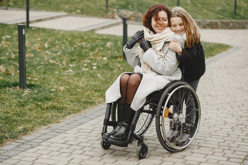 disabled-woman-wheelchair-with-daughter-family-walking-outside-park