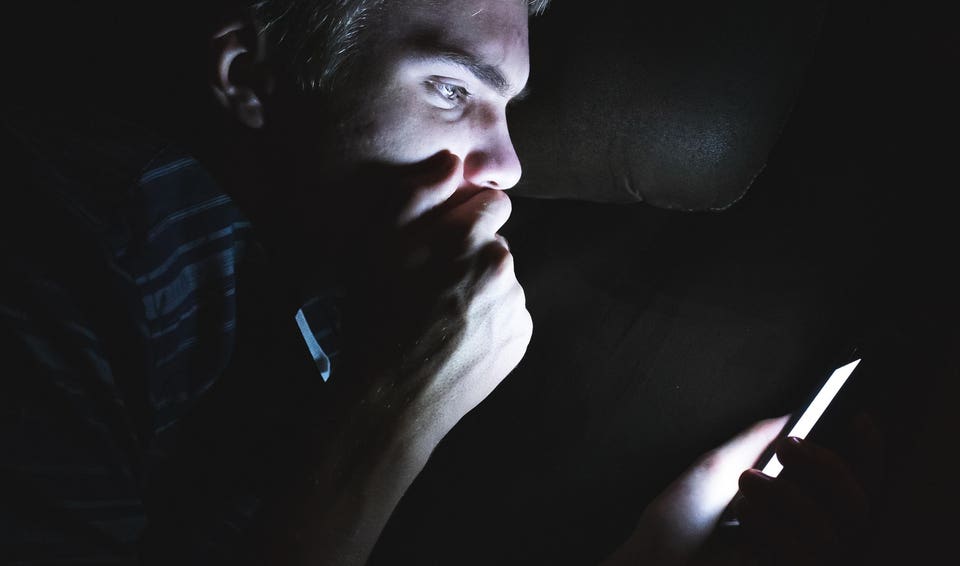 Shocked man on his cellphone in the dark.