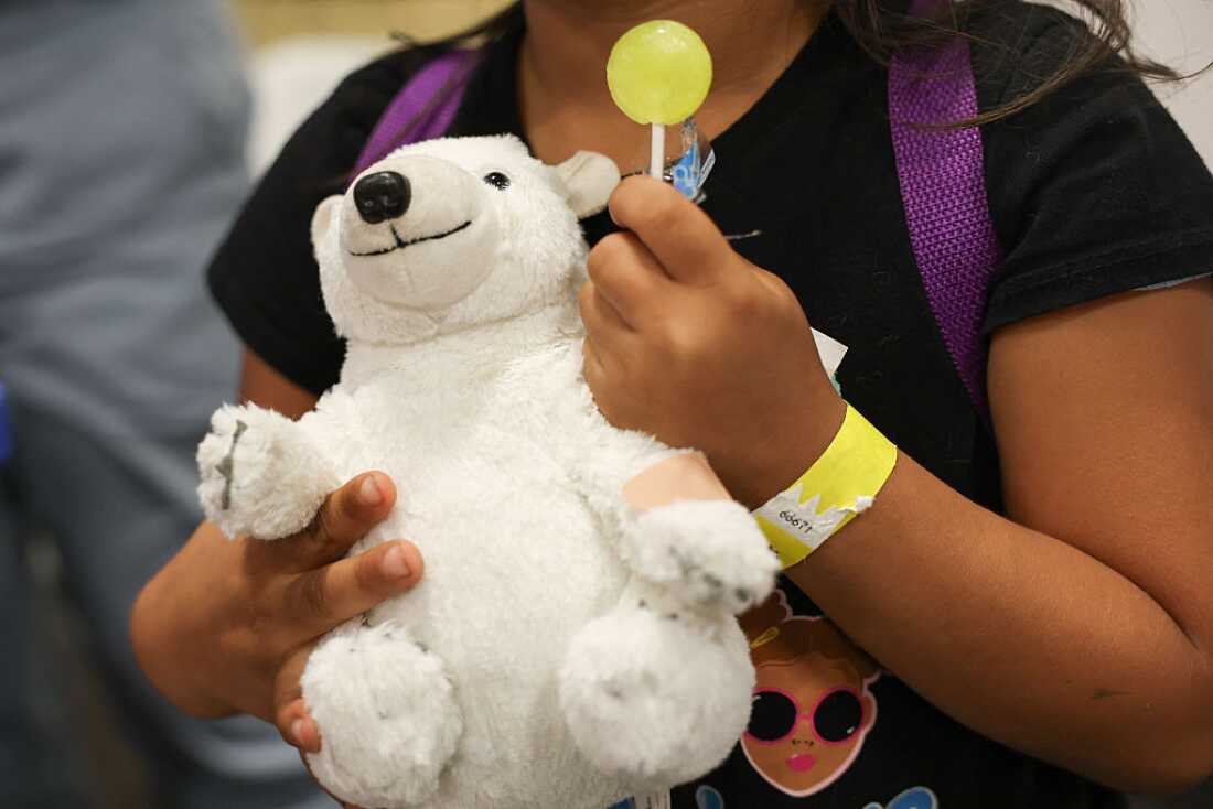 A child holds a toy bear with a band-aid after receiving a flu shot during an immunization event in Los Angeles. Flu is one of six vaccines that will no longer be given routinely but now require a consultation with a doctor.