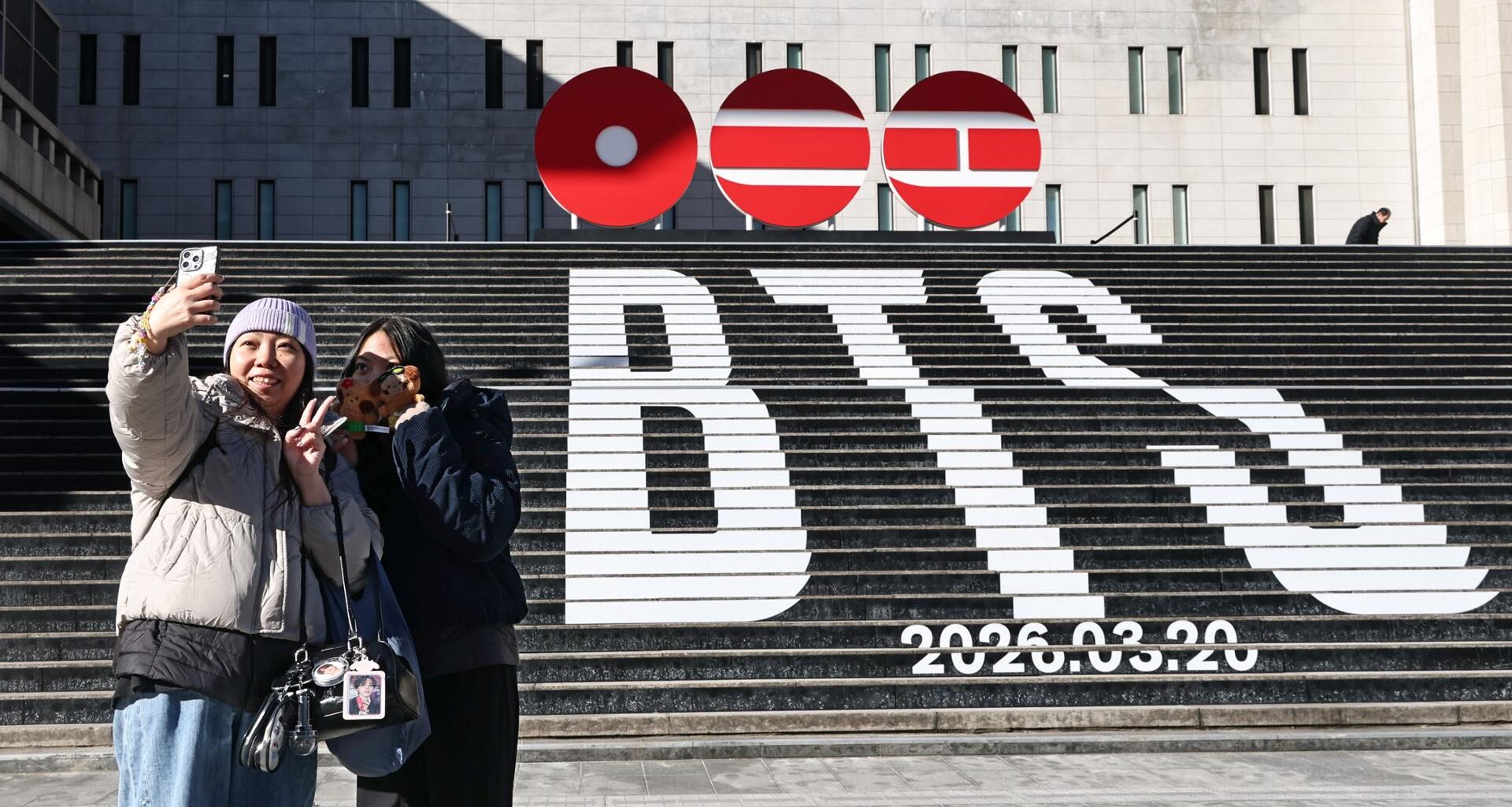 Tourists take a photo of a staircase promoting BTS