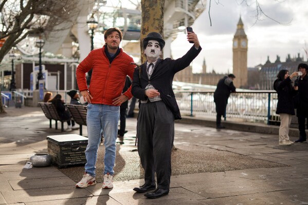 A man takes a selfie with a street artist in a costume, in London, Wednesday, Jan. 28, 2026.(AP Photo/Alberto Pezzali, File)