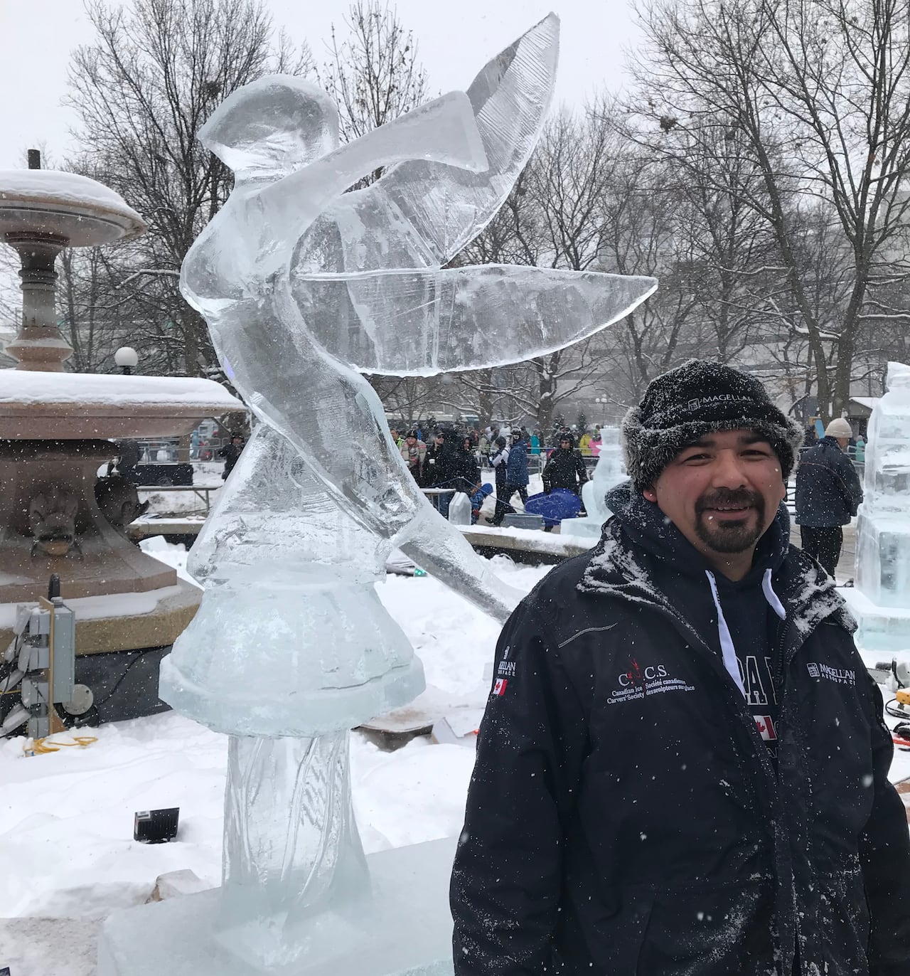 Man stands with mermaid ice sculpture.