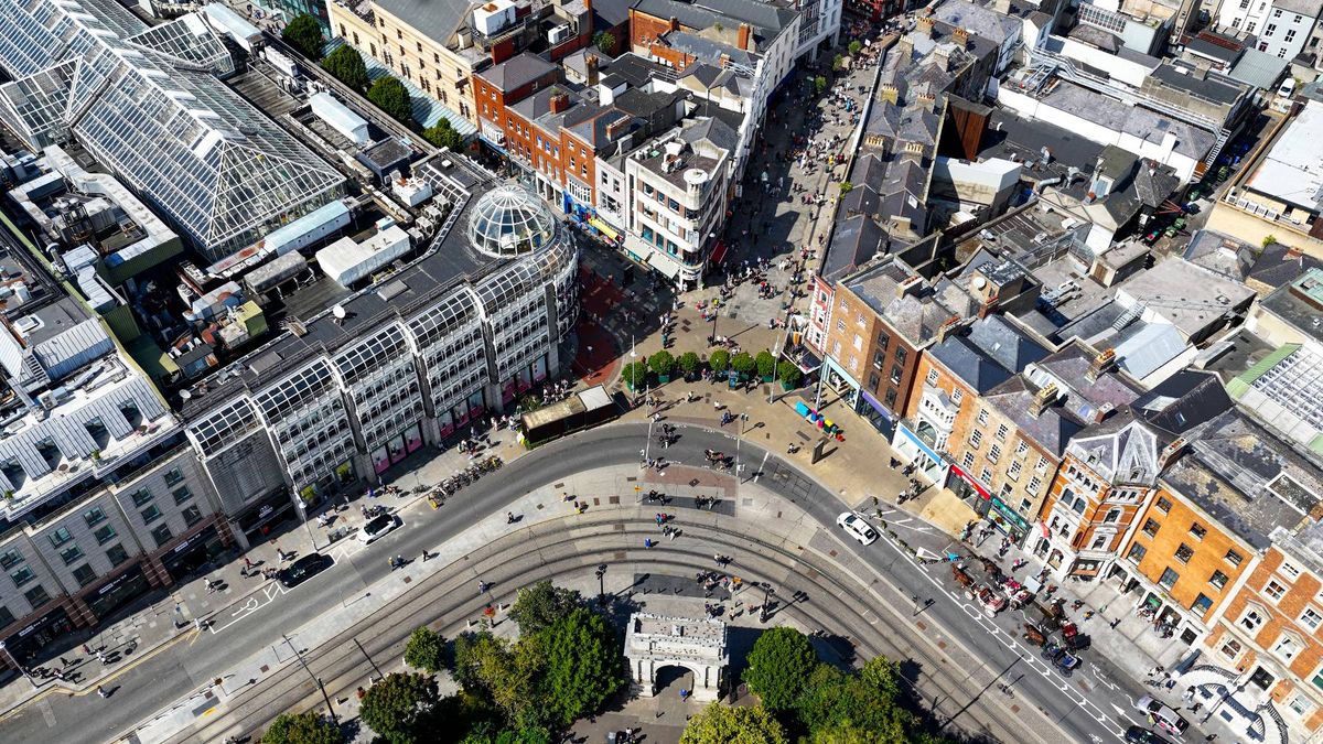 An aerial view of a bustling urban cityscape featuring multiple high-rise buildings, interconnected by a network of roads and railways. The image captures a variety of architectural styles, with modern and traditional structures interspersed throughout the scene.