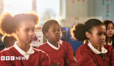 School children in red uniform preparing for relaxation session.