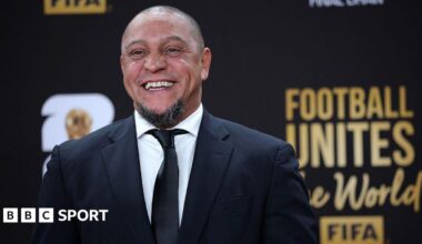 Roberto Carlos smiles for a photo while wearing a suit at the Fifa World Cup draw