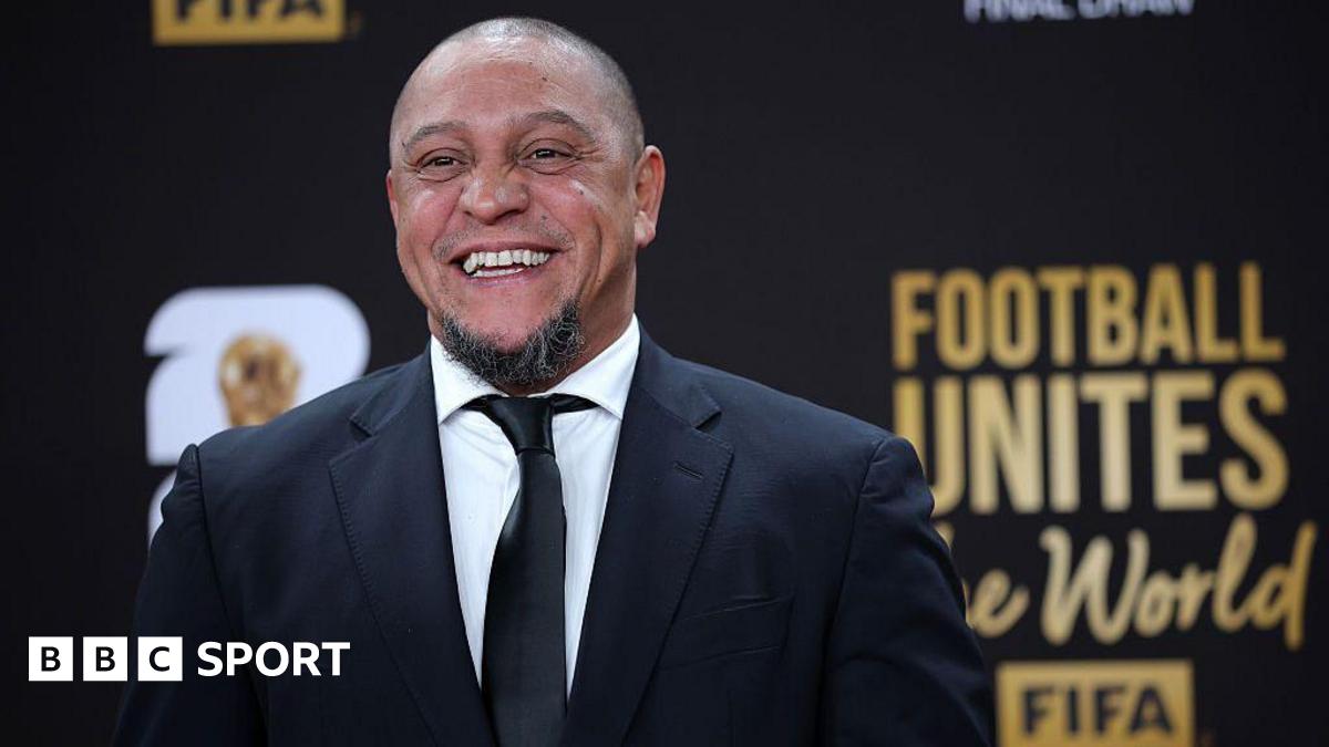 Roberto Carlos smiles for a photo while wearing a suit at the Fifa World Cup draw
