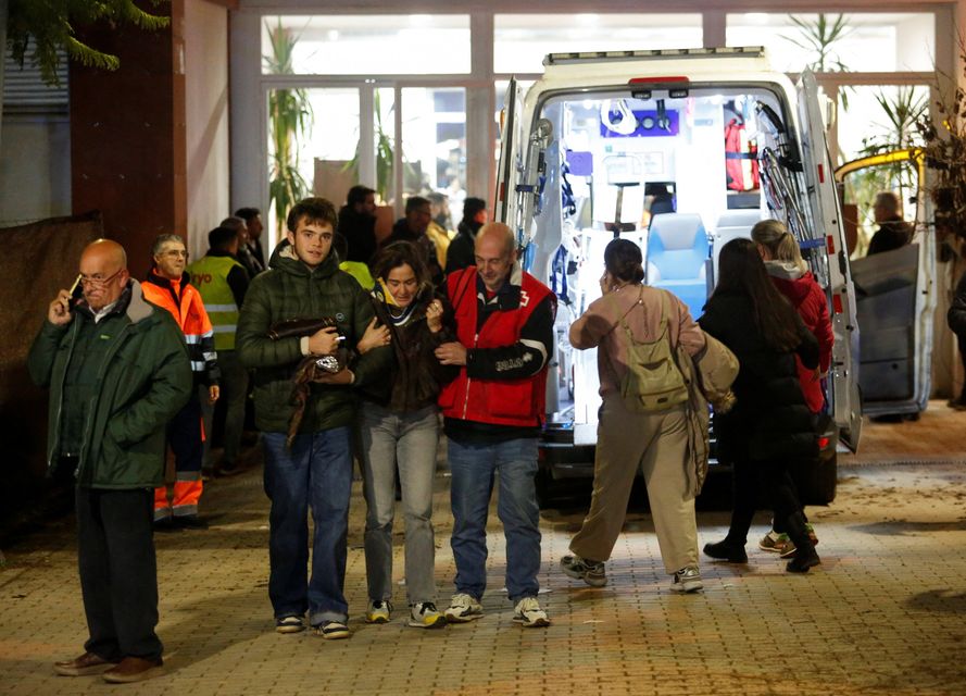 Men assist a woman affected by a deadly train derailment as other victims are transferred and treated at the Caseta Municipal in the town of Adamuz, after a high-speed train derailed and collided with another approaching train near Cordoba, Spain, January 18, 2026. REUTERS/Alex Gallegos