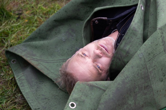 Ray's dead body in a green bag is dragged across the ground in a scene from Emmerdale