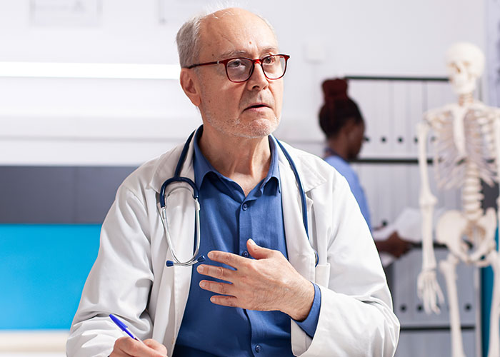 Elderly male doctor with stethoscope making an unprofessional comment to a patient in a medical office setting.