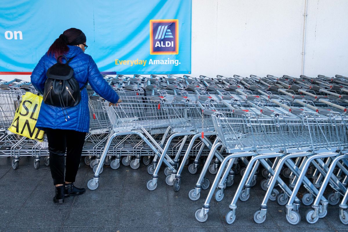 A customer collects a supermarket trolley outside an Aldi