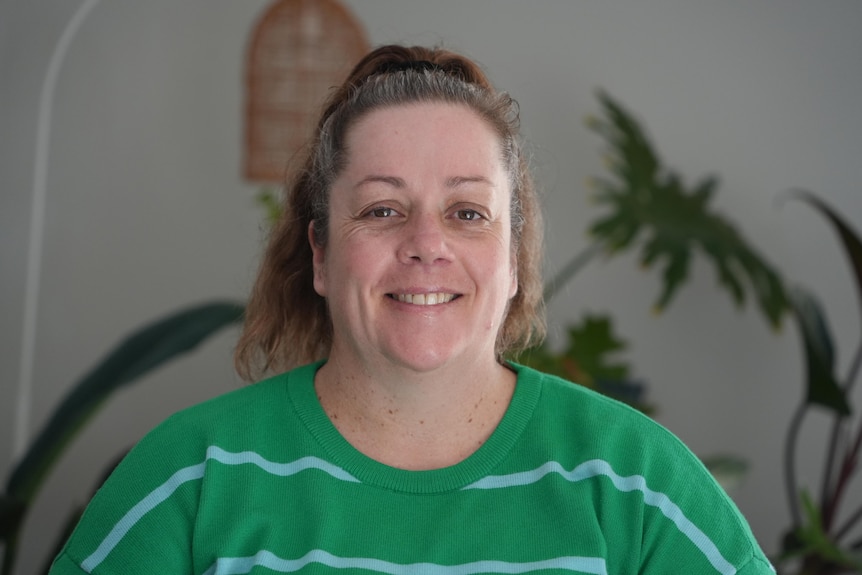 A photo showing a woman wearing a green t-shirt smiling at camera
