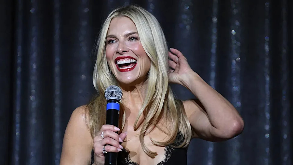Ali Larter smiling and holding a microphone